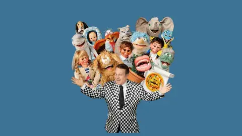 Ventriloquist Joe Gandelman in a white and black checkered suit with all of his puppets above his arms