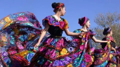 Four dancers perform the Mexican folk dance "baile folklórico" outdoors