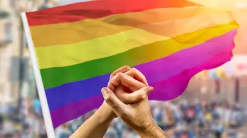 two hands held in front of a rainbow flag