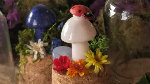 White crystal mushroom with a ladybug on top is surrounded by colorful flowers