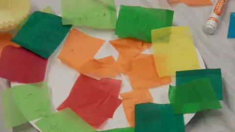 Paper plater with squares of colored tissue paper glued onto it.