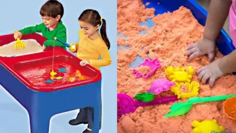 Two children playing at a sand and water table and a pair of small hands grabbing sand.  