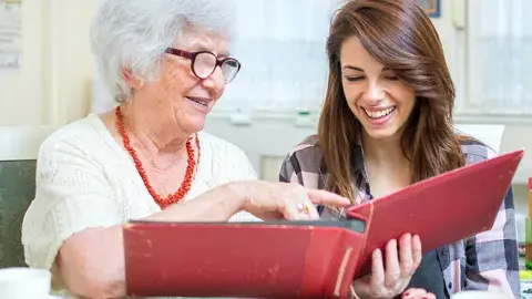 A person helping another person read a book.