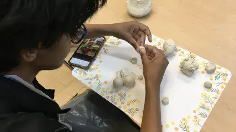 Teen manipulating clay with hands on table