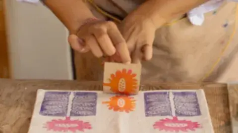 A person stamping a canvas bag at a table