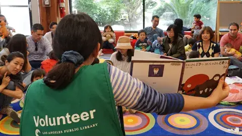 Volunteer reads to a group of families
