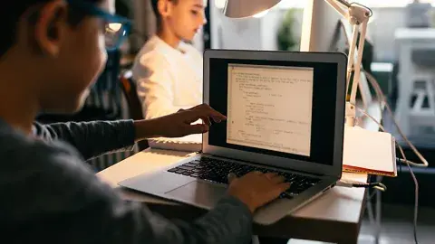 A boy uses his laptop for computer coding