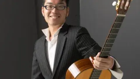 A man holding a guitar and looking at the camera 