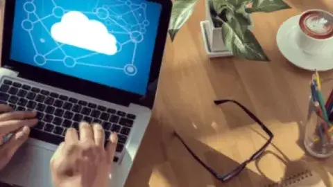 Computer on a desk with hands on keyboard