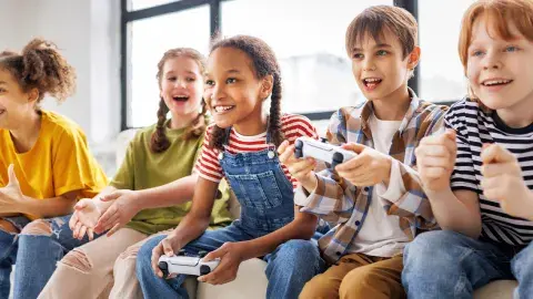 Young people sitting and playing video games with controllers in their hands.