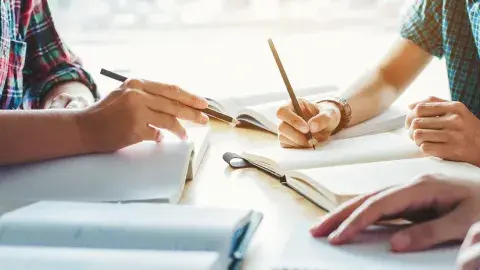 Three adults writing on a notebook.