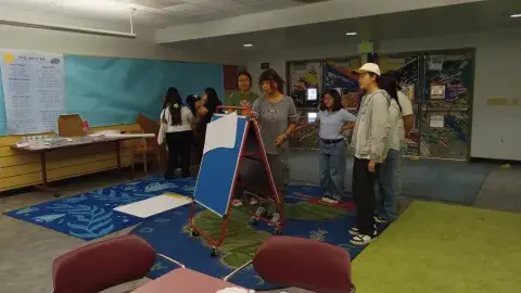 Teen council members stand around a white board brainstorming ideas