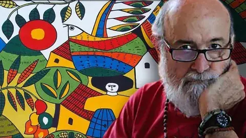Fernando Llort with his art in the background.