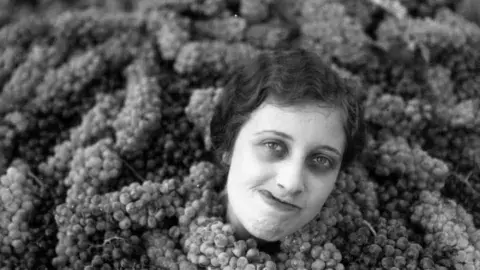 woman covered up to her neck in grapes