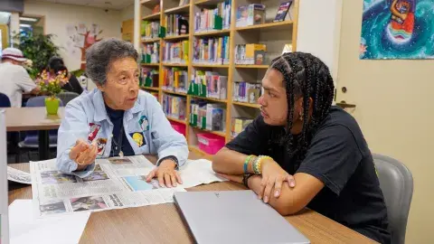 tutor works with student using newspaper
