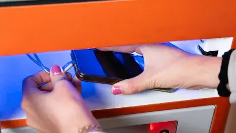 person's hands plugging smartphone into charging station