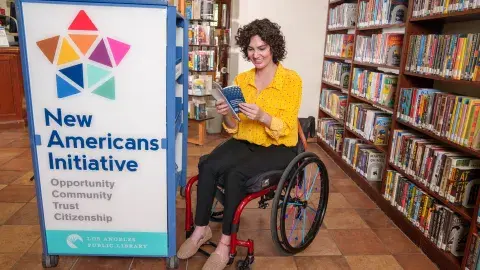 person using wheelchair peruses materials at the New Americans Center