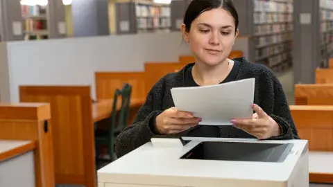 person gathers printed paper from printer