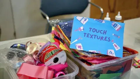 boxes of ribbon and materials that read "touch textiles"