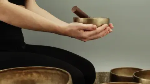Hands cup a singing bowl