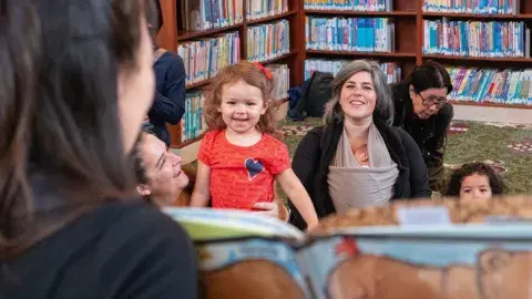 librarian reading a book to a small group of children and adults