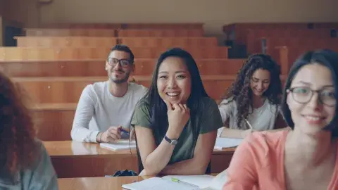 A Group of happy students in a classroom sitting in their seats and enjoying their lesson