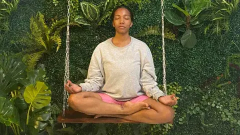 a woman sits with her legs crossed and eyes closed