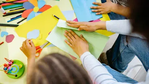 Children doing crafts with colorful construction paper. 