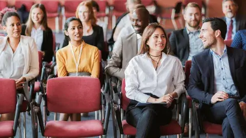A group of people sitting in chairs, lecture style. 