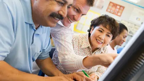 Mature students learning computer skills in a classroom.