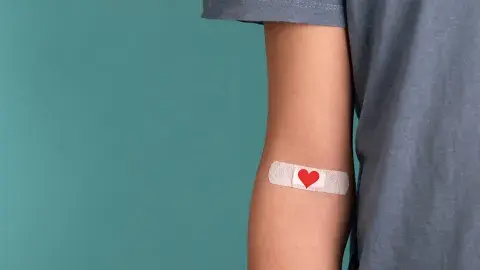An arm with a heart-themed band-aid affixed 