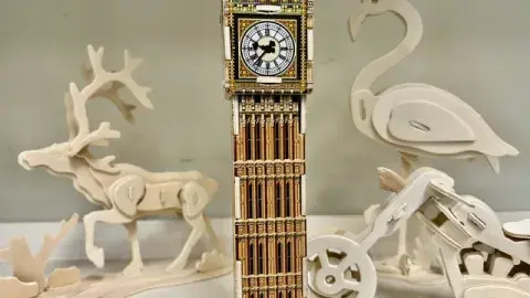 A variety of 3D wooden puzzles of animals, a building and a vehicle.