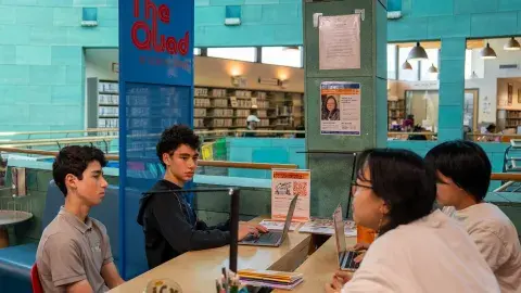 students sitting at table in teen quad