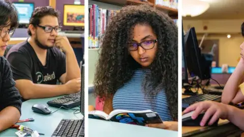 Various students sitting down looking at a computer or reading a book.