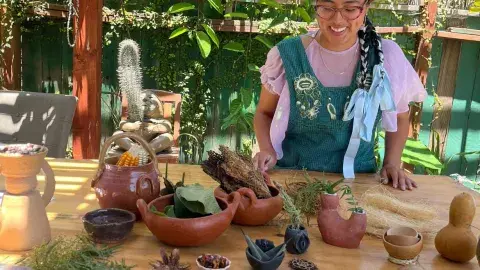 A woman wearing an apron in front of handmade clay objects. 