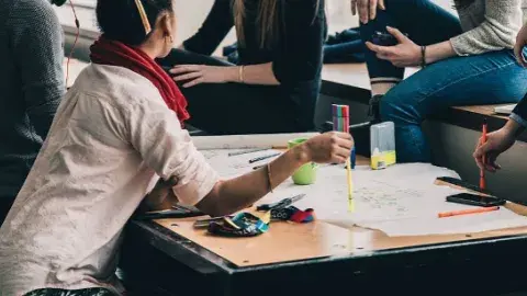 Teens sitting around a table with papers spread out.
