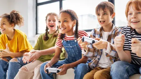 Young people sitting on a couch and playing video games with controllers in their hands.