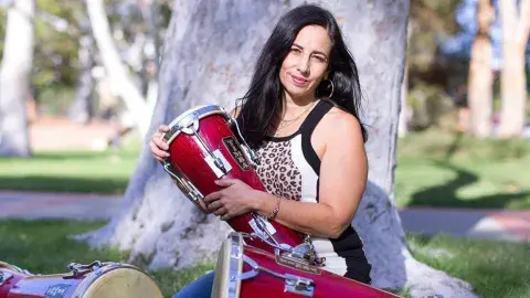 Woman sitting outdoors with three drums