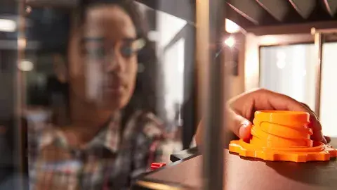 Person reaching into the a 3D printer, to touch a 3D print