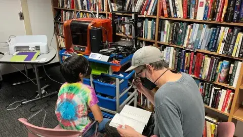 Two patrons in front of 3D printers