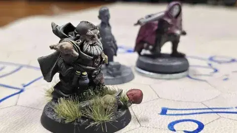 3 painted fantasy character miniatures side by side on a hexagon grid play mat