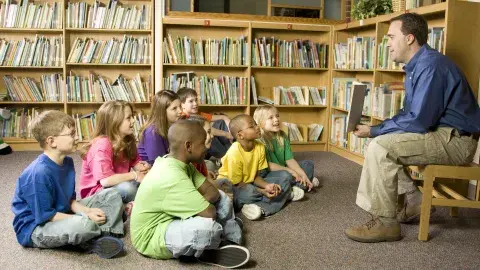 A man reads to a group of young students