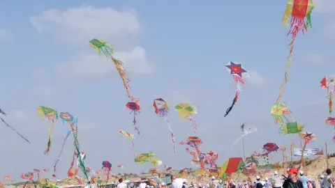 Children fly colorful homemade kites on a beach.