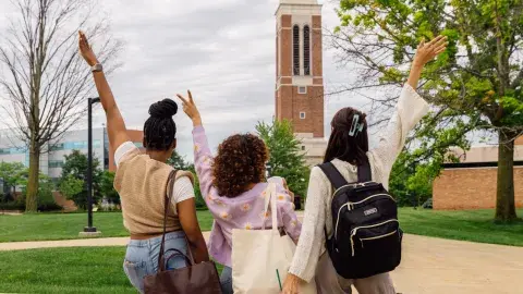three college aged people facing a university building