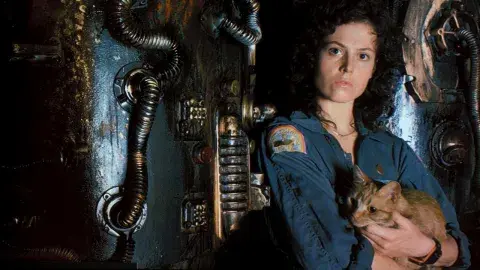 Sigourney Weaver in uniform as Ripley pictured holding her tabby cat