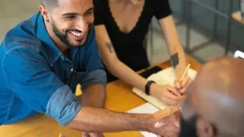 Man sitting across from two people shaking hands