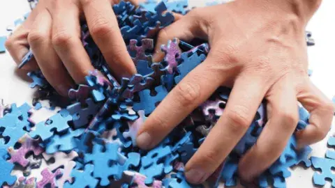 Two hands play with blue and purple puzzle pieces