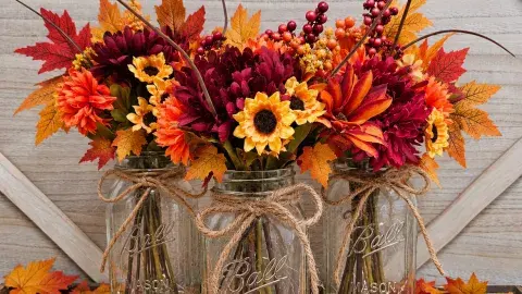 mason jars with fall colored artificial leaves and flowers