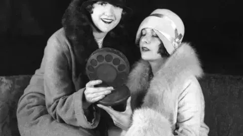 2 women holding an old fashioned microphone
