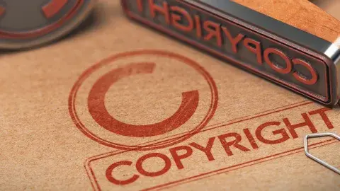 A copyright symbol printed in a piece of brown paper with a metal stamp placed on top.
